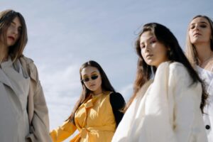 Fashionable women posing confidently in chic outfits under the clear sky.